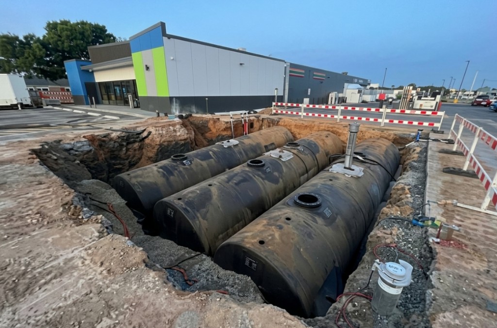 Three underground storage tanks set in an open excavation at a convenience store fueling site